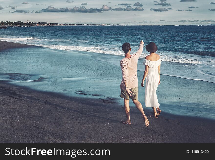 Couple walking on beach. Young happy couple walking on beach smiling holding around each other.