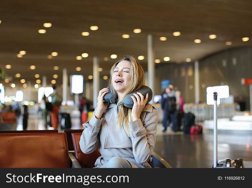 Pretty Lady Sitting With Neck Pillow And Valise In Airport Waiting Room.