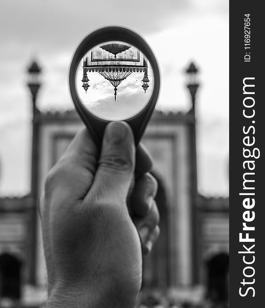 Grayscale Photo of Person Holding Round Magnifying Glass