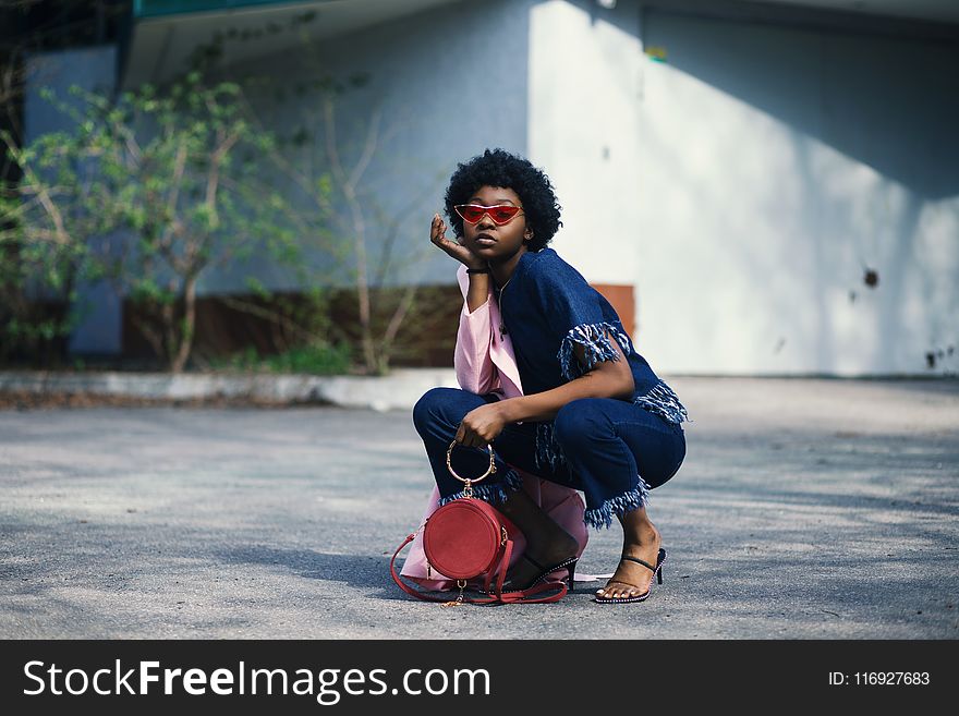 Woman Wearing Blue Shirt and Pants Holding Red Leather Barrel Bag