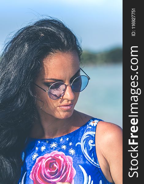 Shallow Focus Photography of Woman Wearing Blue Floral Sleeveless Top and Black Sunglasses With Gray Frames