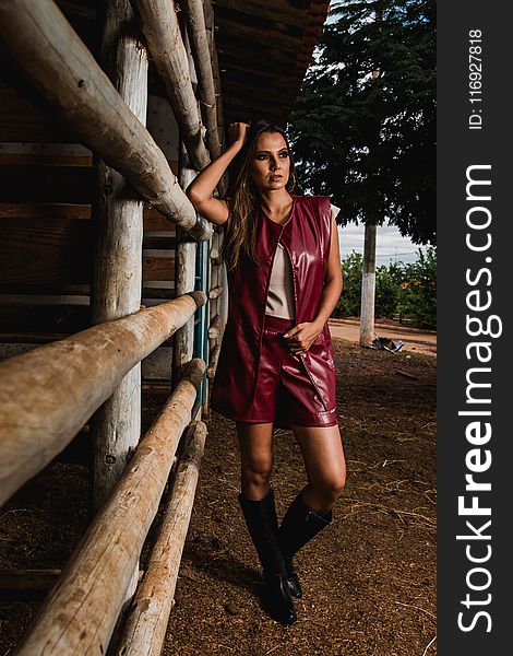 Woman Wearing Maroon Leather Sleeveless Jacket Beside Horse Stable