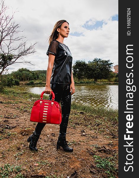 Woman Wearing Black Suit Holding Red Leather Duffel Bag during Day