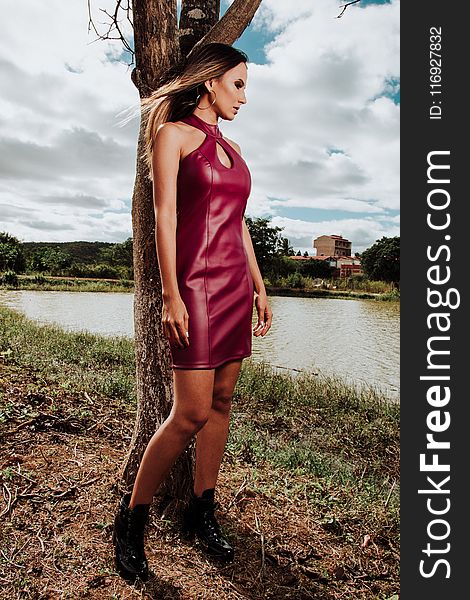 Woman in Red Leather Halter Keyhole Midi Dress Leaning on Brown Tree