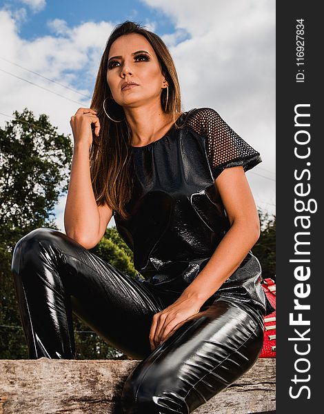 Woman in Black Leather Pants Sitting on Log