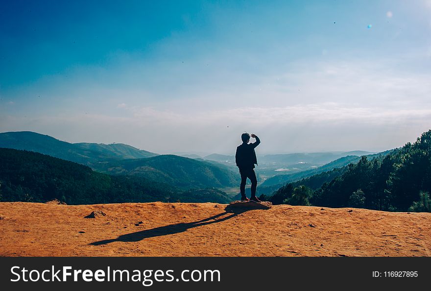 Silhouette of Man Standing on Mountain Cliff