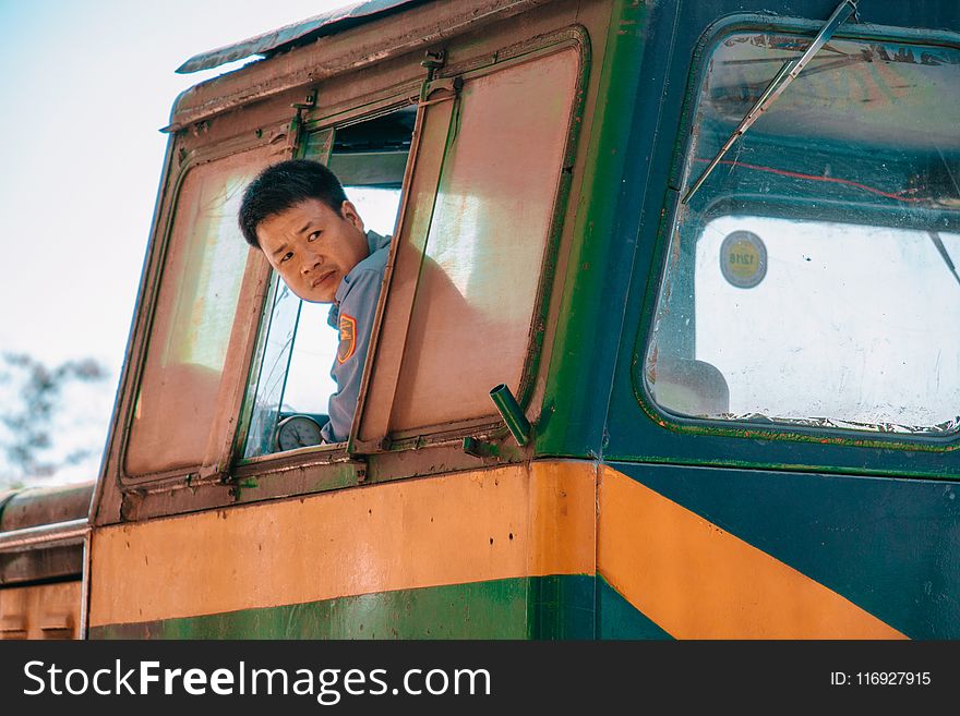 Man Wearing Blue Shirt Driving Green And Yellow Vehicle