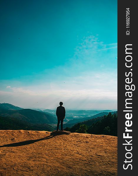 Silhouette of Person Standing on Hill Under Clear Blue Sky