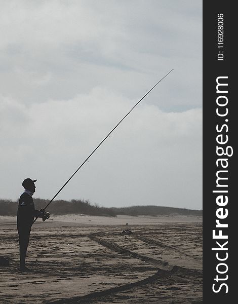 Man Standing Holding a Fishing Rod