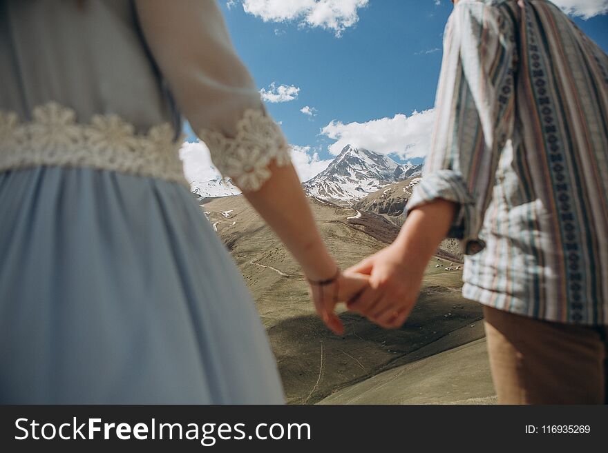 Big mountain with a snowy peak between the hands of a loving couple in sunny. Big mountain with a snowy peak between the hands of a loving couple in sunny