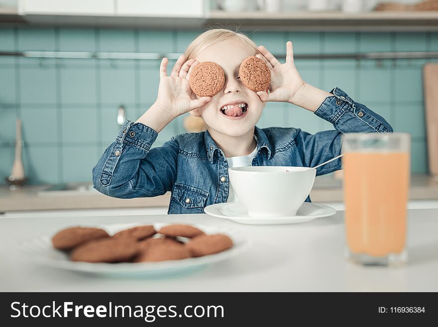 Moment of happiness. Beautiful kid showing her tongue while making faces, being in the kitchen. Moment of happiness. Beautiful kid showing her tongue while making faces, being in the kitchen