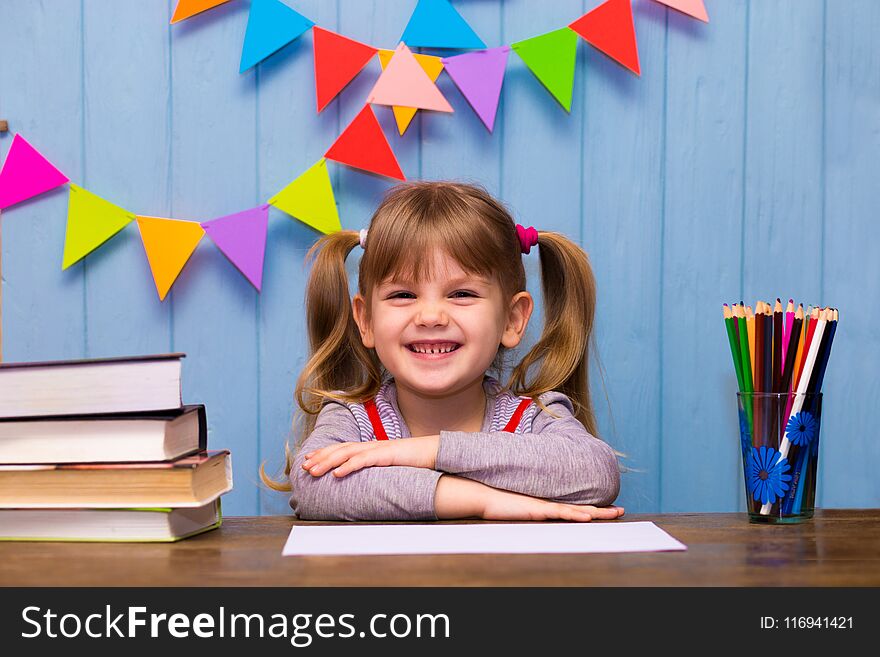 Portrait of lovely girl in classroom. Little schoolgirl sitting at desk and studying. Education and school concept - little girl with many books at school