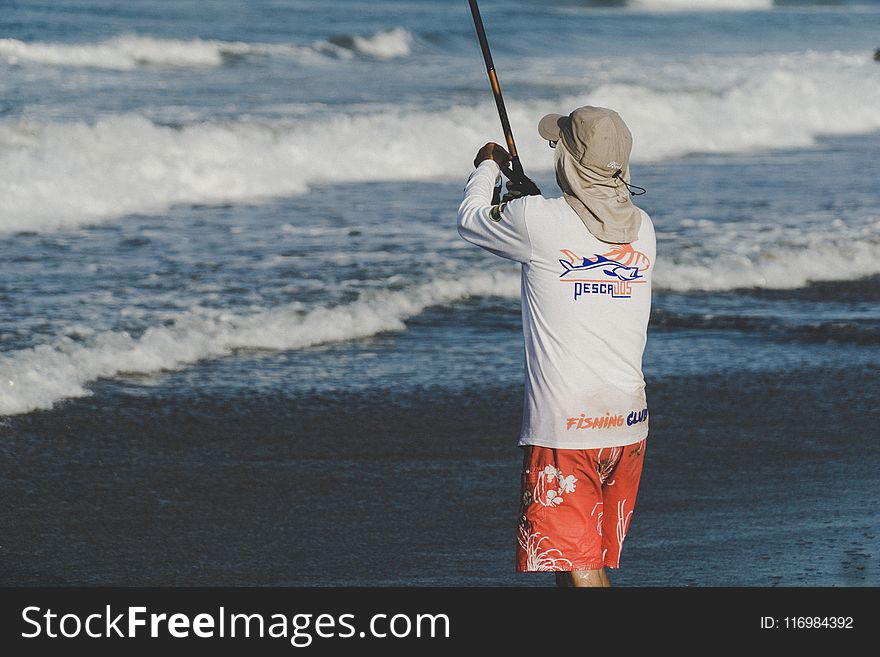 Person Holding Fishing Rod On Beach