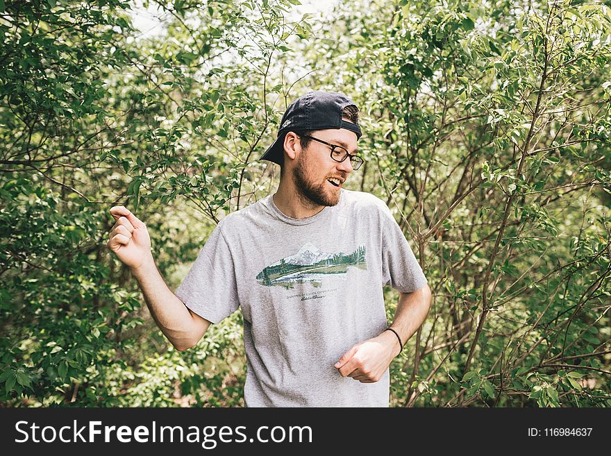 Man Wearing Gray Crew-neck T-shirt Standing Behind Bush