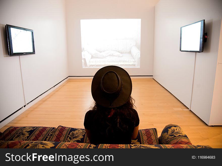 Woman Sitting on Red-and-green Suede Sofa Facing Well Lighted Room