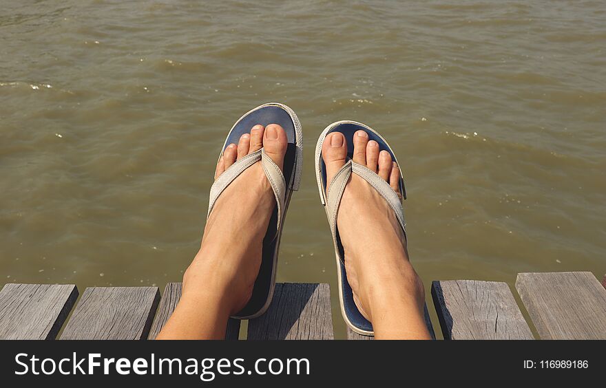 Blue Fabric Flip Flops on Wooden Dock - Muddy Rough Water. Blue Fabric Flip Flops on Wooden Dock - Muddy Rough Water