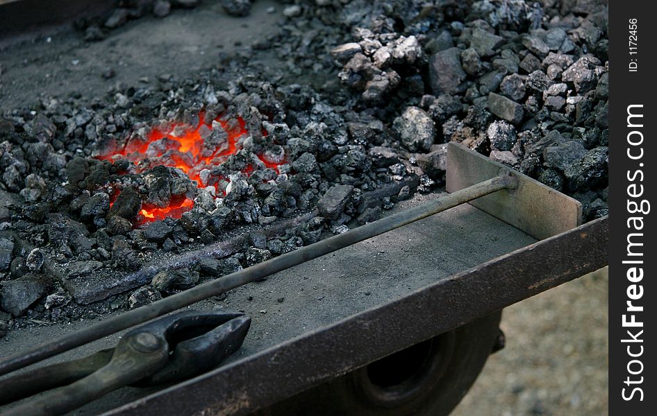 The tools of a medieval blacksmith next to hot embers. The tools of a medieval blacksmith next to hot embers.