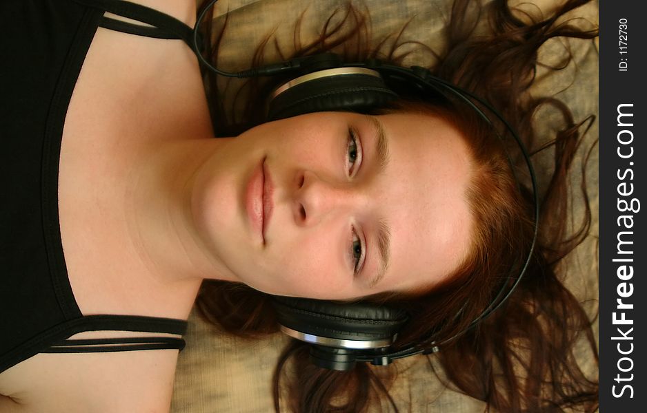 A teenager with headphones lying on a sofa. A teenager with headphones lying on a sofa.