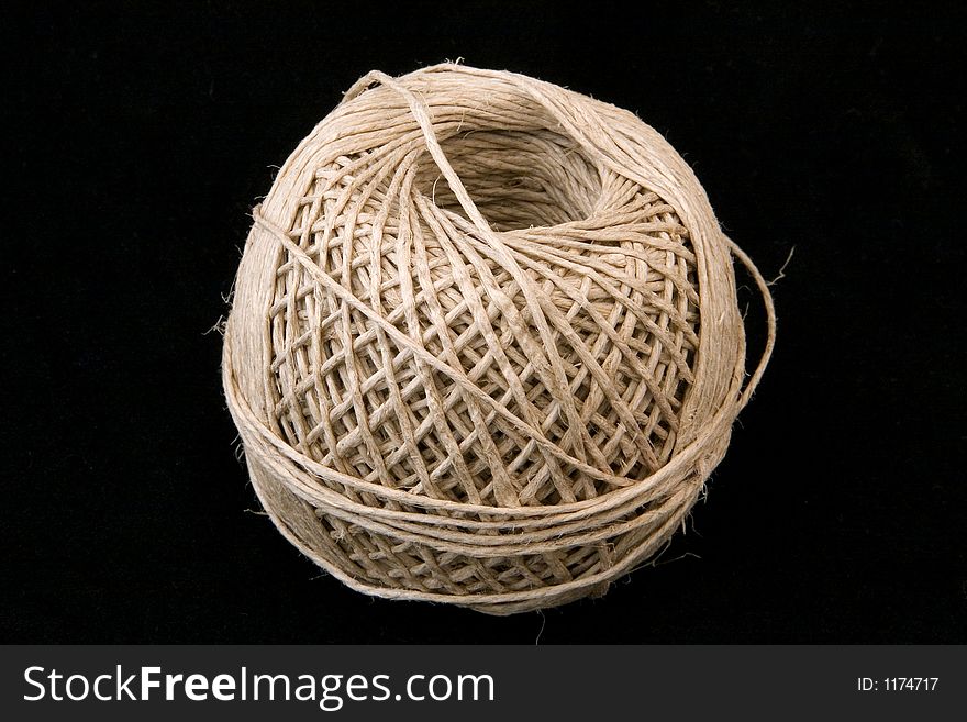 A large ball of neatly wound string on a black background.