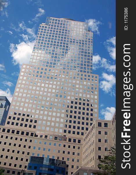 A tall building in ny city with a blue sky and clouds reflecting in it. A tall building in ny city with a blue sky and clouds reflecting in it.