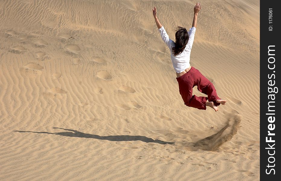 Girl doing a Charlie Chaplin leap in the dunes in Maspalomas. Girl doing a Charlie Chaplin leap in the dunes in Maspalomas