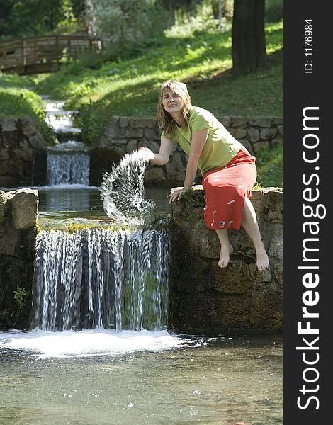 Blond lady is splashing water in the water fall. Blond lady is splashing water in the water fall.