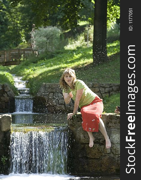 Blond lady is splashing water in the water fall. Blond lady is splashing water in the water fall.