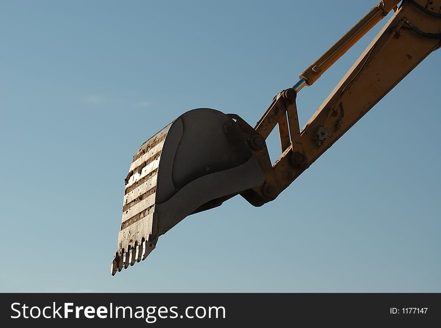 Close-up shot of trackhoe bucket at work against the blue sky morning. Close-up shot of trackhoe bucket at work against the blue sky morning.