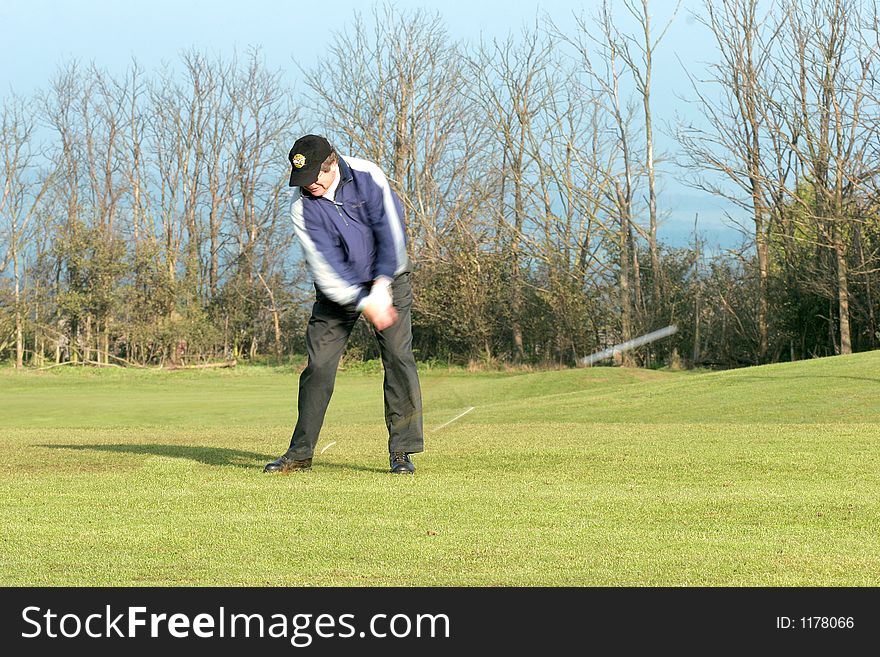 A golfer taking a shot and the ball is blurred