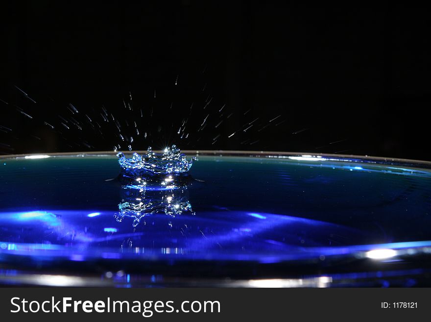 A blue water drop with a blurred splash. A blue water drop with a blurred splash