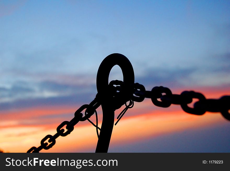 Silhouette image of a steel chain through the hole during sunset to describe connection. Silhouette image of a steel chain through the hole during sunset to describe connection.