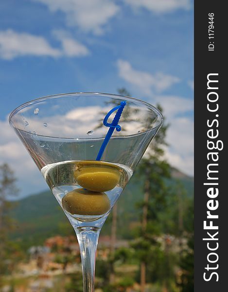 Martini with olives against the backdrop of a partly cloudy blue sky. Martini with olives against the backdrop of a partly cloudy blue sky