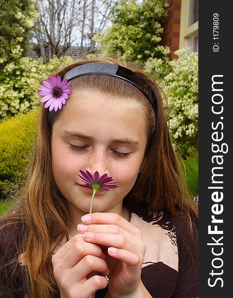 Beautiful young girl smelling flower