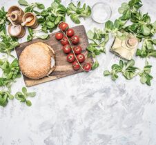 Cooking A Homemade Burger Chicken Cutlet, And A Side Dish Of Salad With Cherry Tomatoes, Seasonings And Oil, On A White Rusti Stock Images Cooking A Homemade Burger Chicken Cutlet, And A Side Dish Of Salad With Cherry Tomatoes, Seasonings And Oil, On A White Rusti Stock Images
