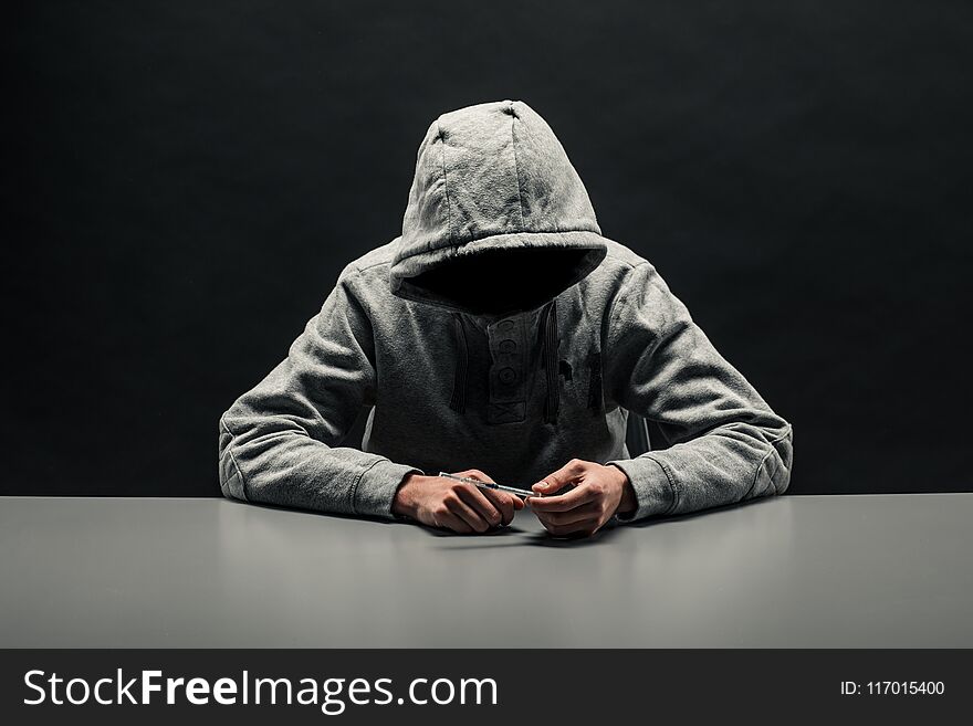 Addict in gray hoodie on the head suffers from addiction on a dark black background.