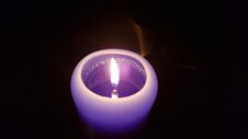 Tiny Light Of Purple Candle In The Darkness Royalty Free Stock Photos