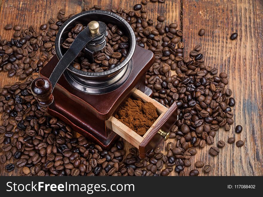 Coffee mill on rustic wooden plank background and roasted coffee beans. Food and drink retro and vintage concept.