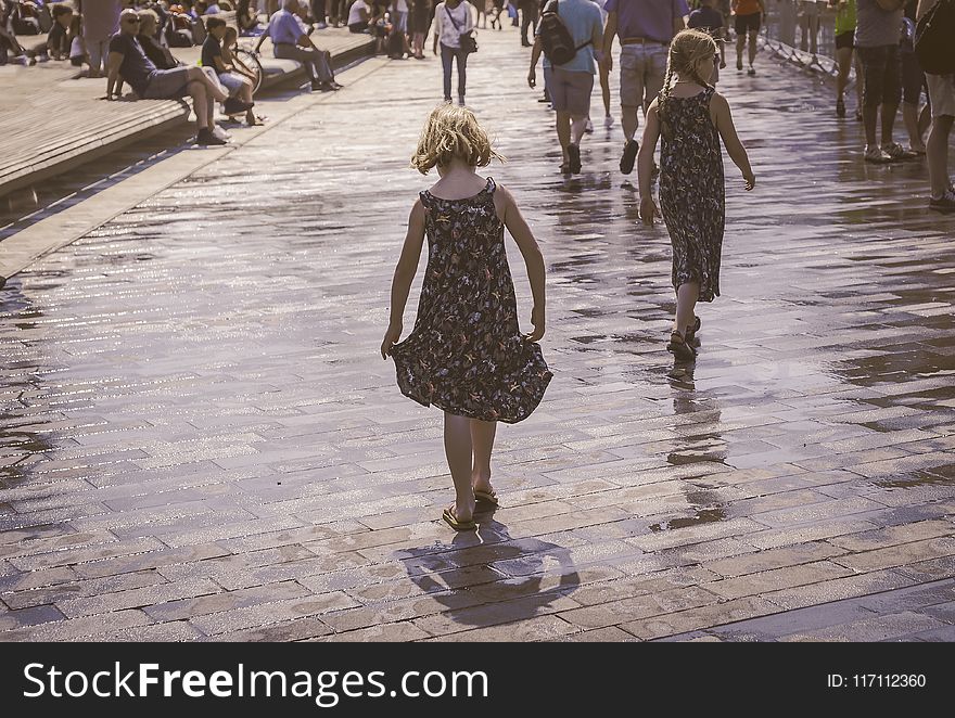 Grayscale Photo of Two Woman Walks on Bricks Pavement Front of People at Daytime