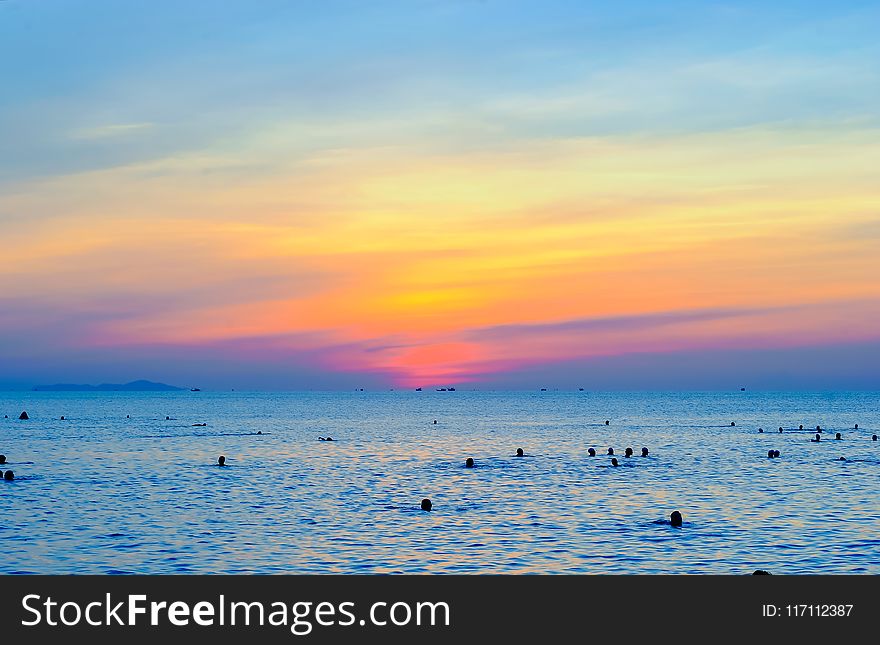 People Swimming On Sea During Golden Hour