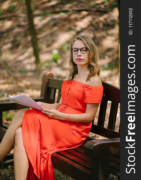 Woman Sitting On Brown Wooden Bench