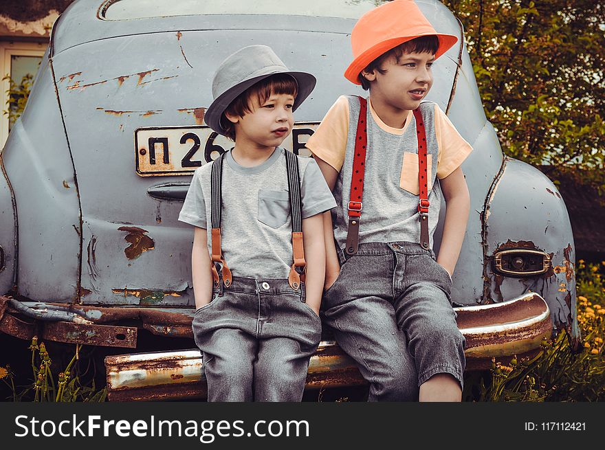 Two Boys Sitting on Vehicle Bumper