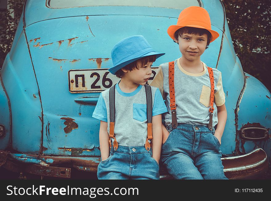 Two Boys Sitting On Blue Volkswagen Beetle Coupe&x27;s Rear Bumper