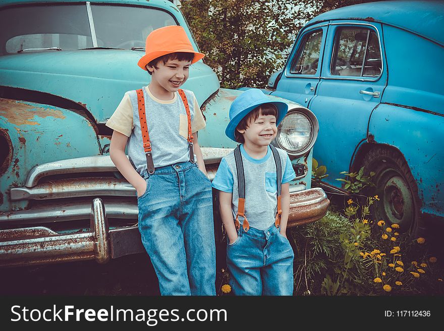 Two Boys Leaning on Classic Teal Vehicle