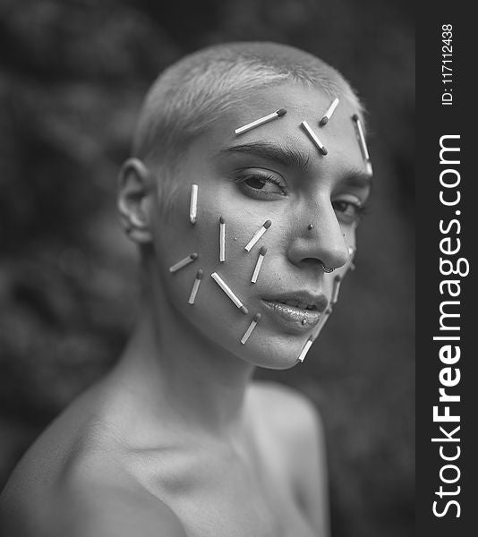 Grayscale Photo of a Person With Matchsticks on Face