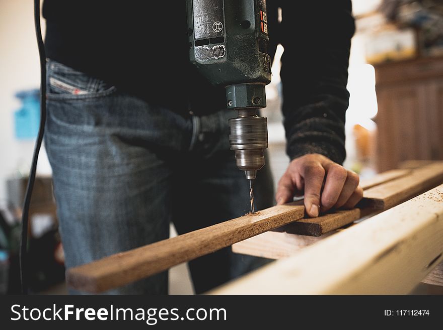 Man Holding Wooden Stick While Drilling Hole