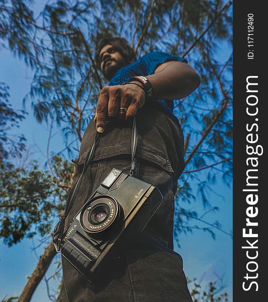 Worm&x27;s View Of Man Holding Camera Under Blue Calm Sky