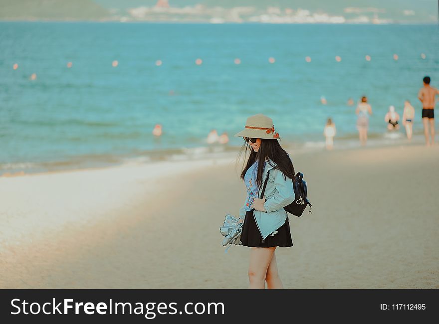 Girl in Cyan Jacket Walking on Beach