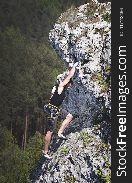 Man Wearing Black Tank Top And Brown Shorts Climbing Rock