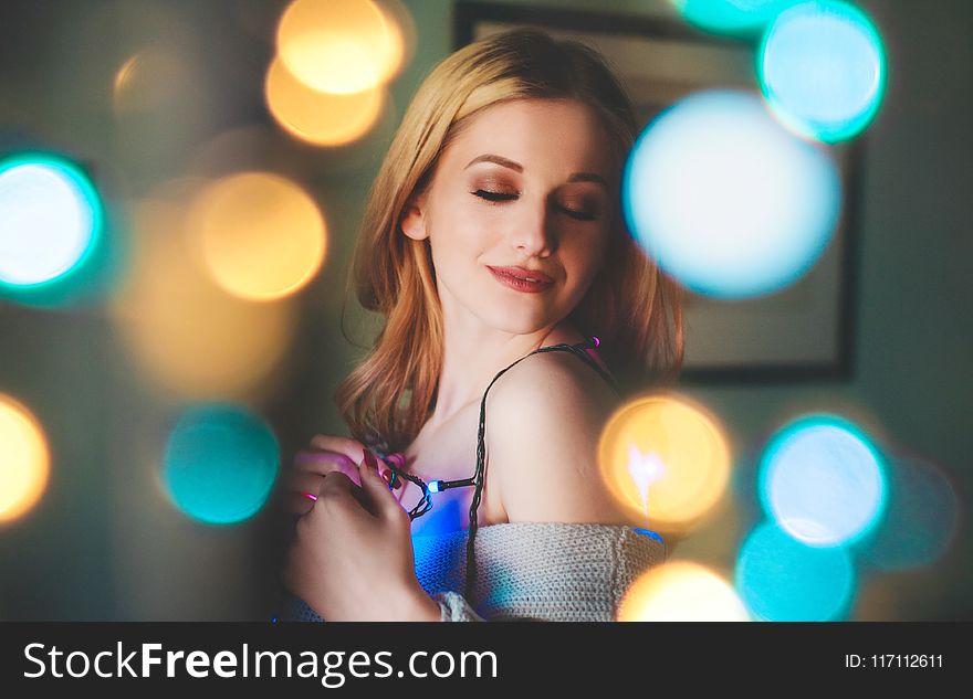 Woman In Grey Strapless Dress Holding String Lights Smiling With Bokeh Lights