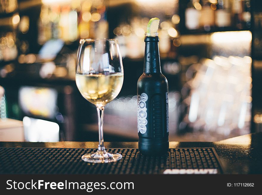 Black Bottle Beside Long-stem Wine Glass On Table